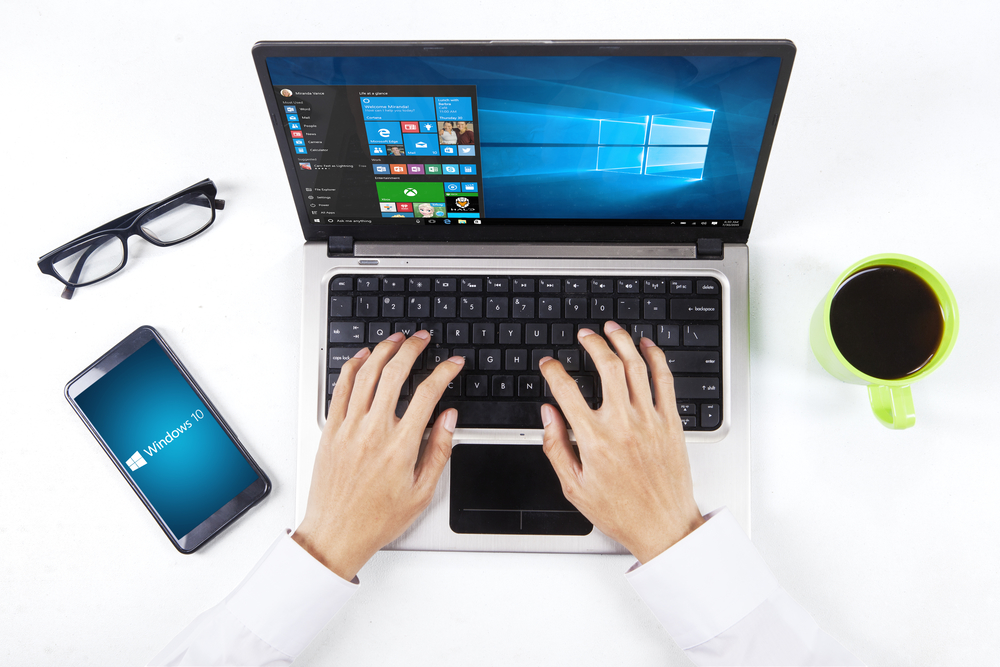 Hands using windows 10 on laptop and smartphone
