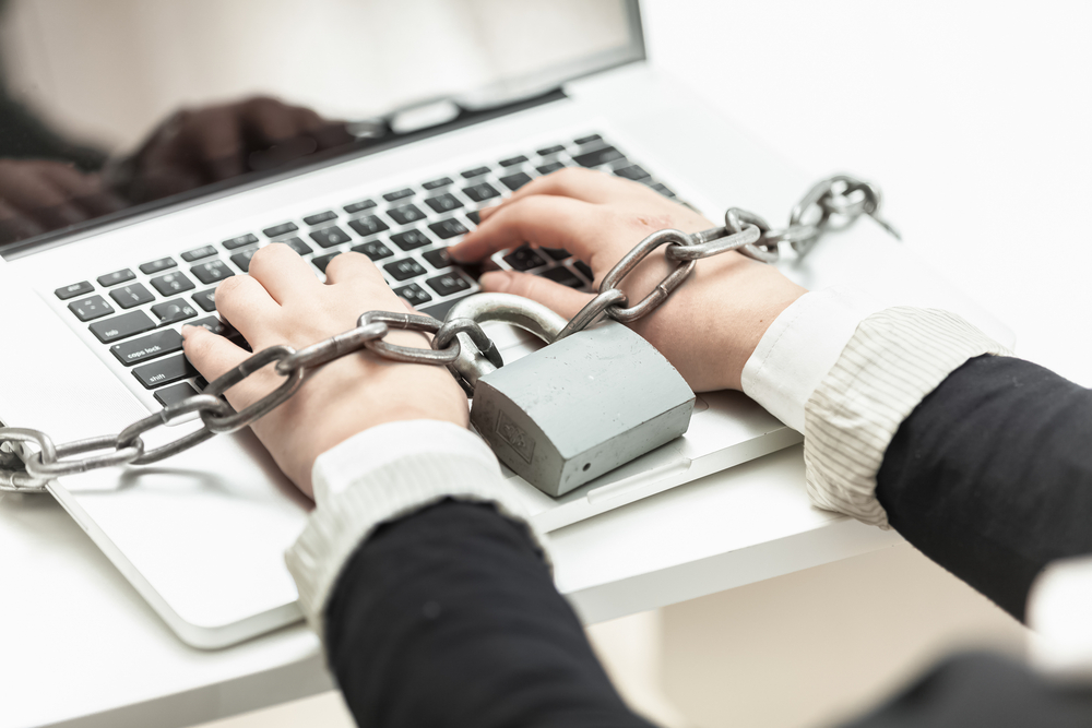 woman locked in chain typing on laptop