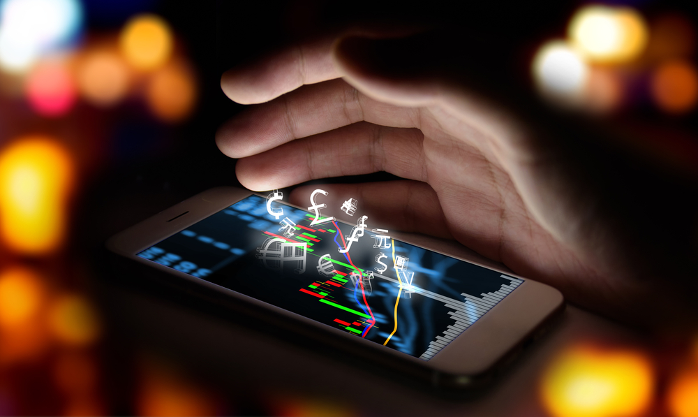 currencies-sign-icon-and-smartphone-with-stock-market-graph-screen-and-hand-with-bokeh-blur-background-blockchain-fintech-investment-financial-internet-technology-concept