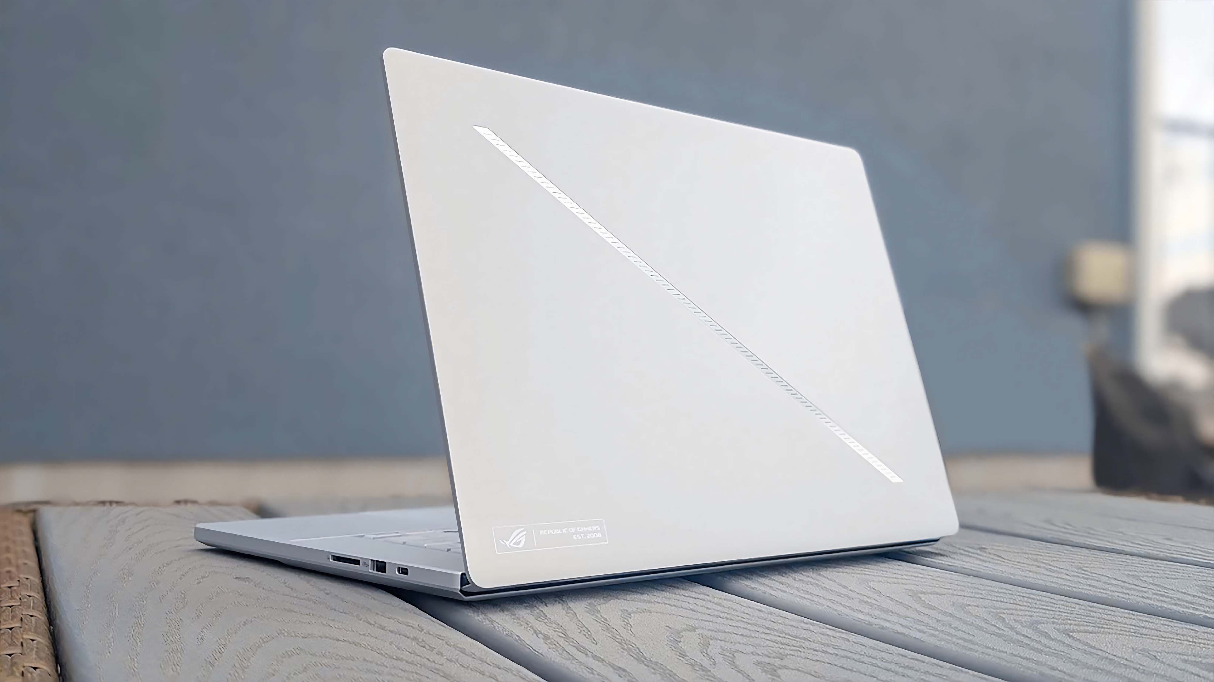 ASUS ROG Zephyrus G16 (GU605C, 2025) на сером столе с подсветкой Slash на крышке.