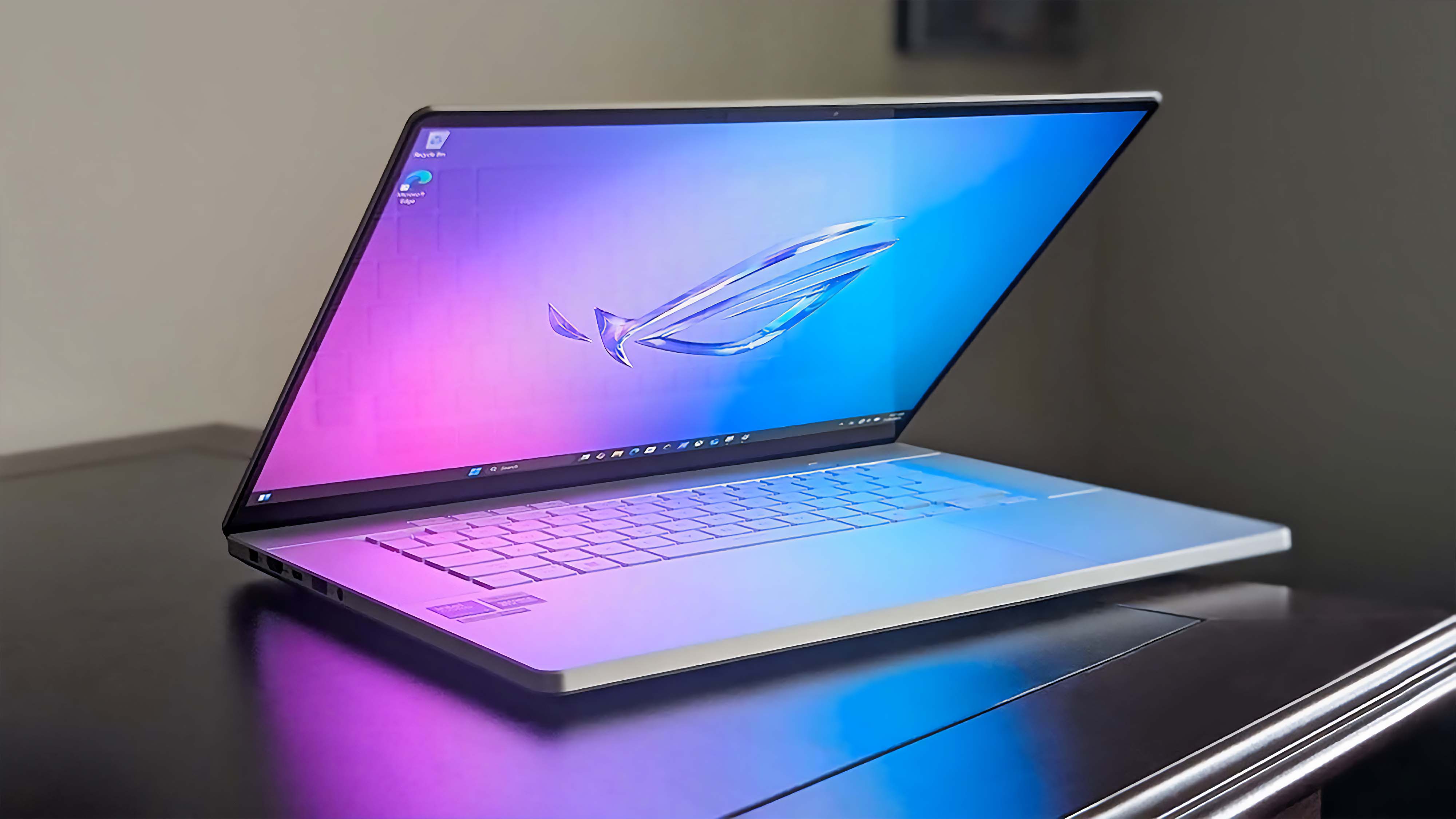 ASUS ROG Zephyrus G16 (GU605C, 2025) на столе в темной комнате с полузакрытой крышкой.