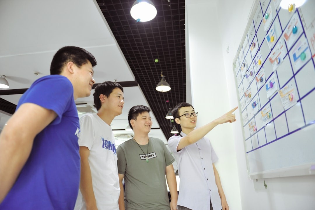 Four men gathered around a whiteboard with sticky notes.