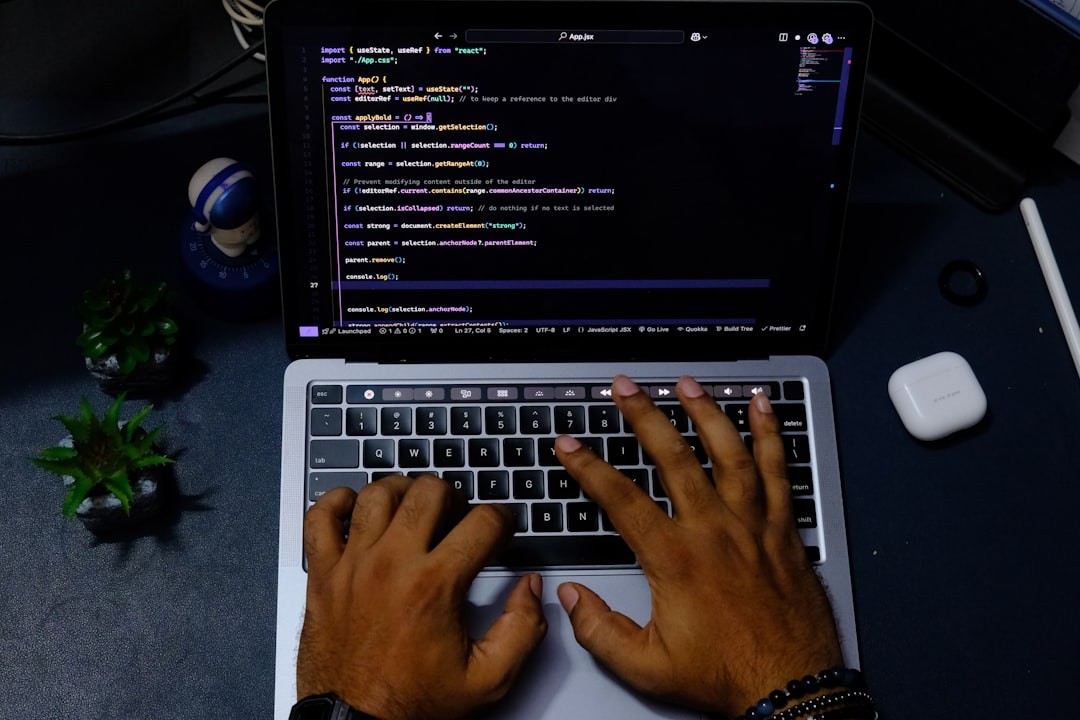 Hands typing code on a laptop computer.