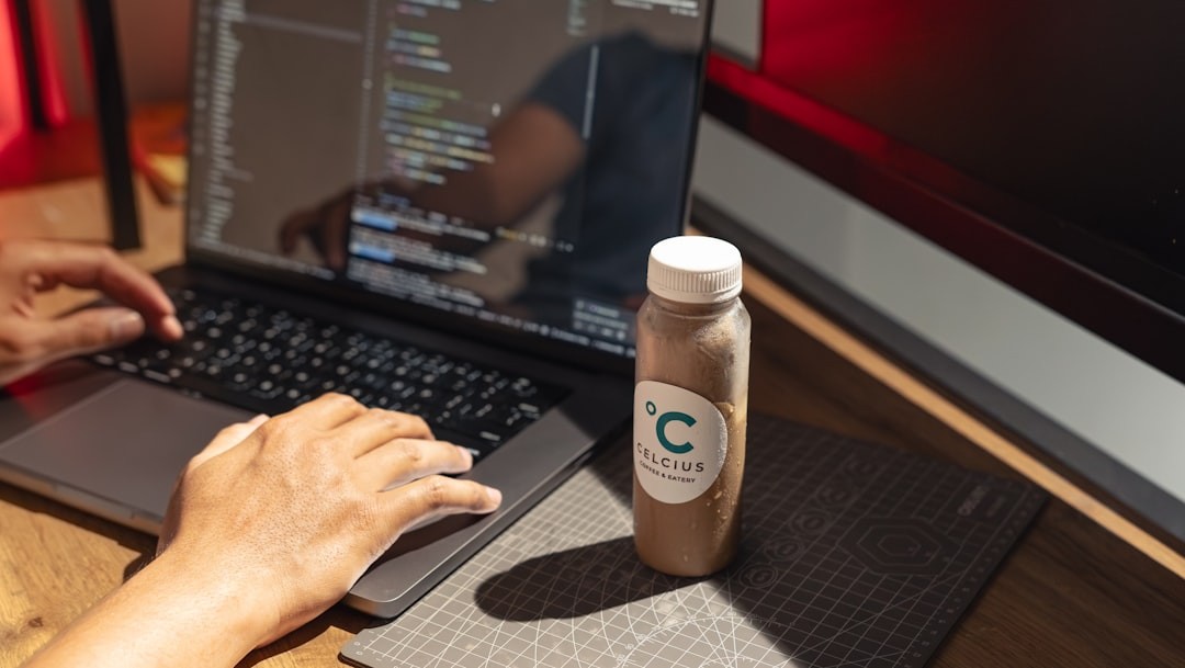 Person typing on laptop with drink beside them