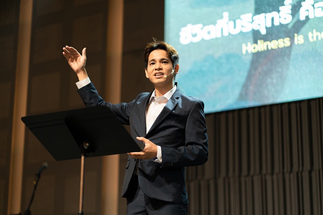 A man in a suit speaks on a stage.
