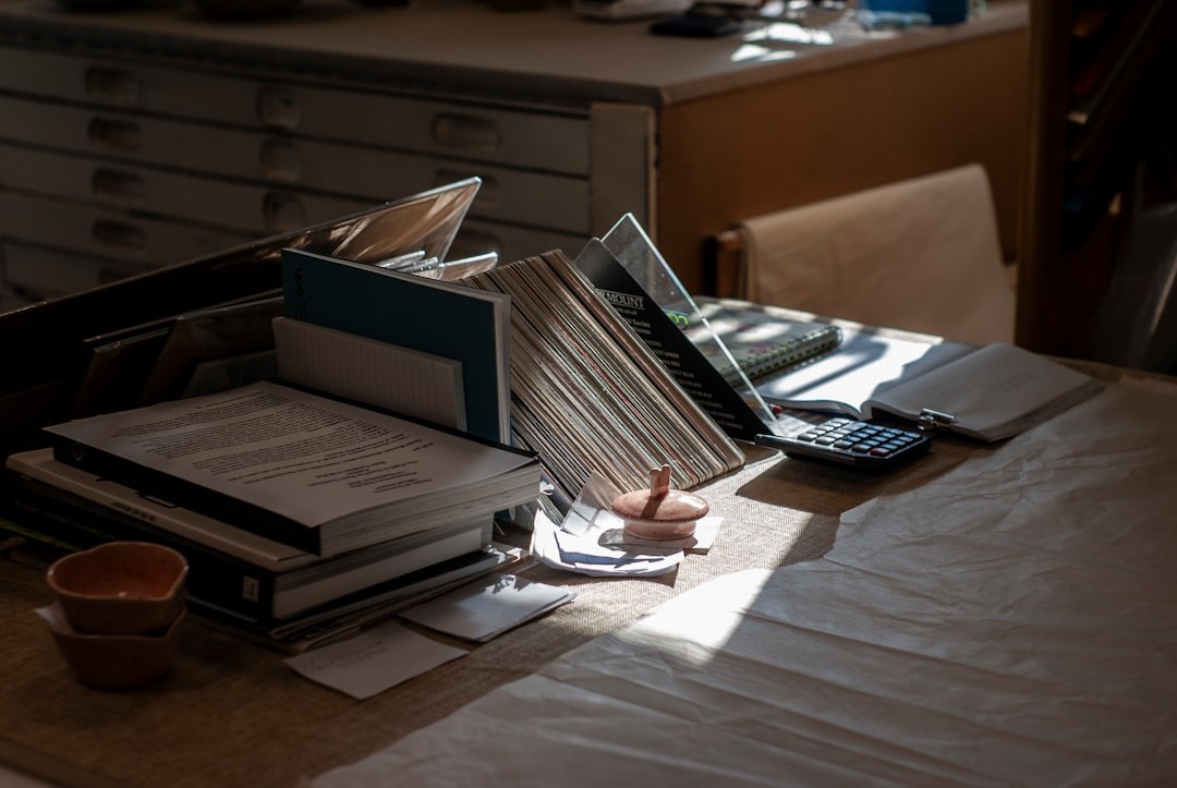 Desk with books, papers, and calculator in-tray