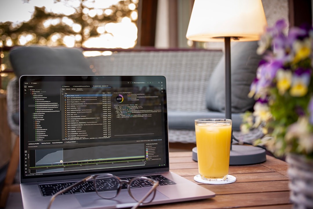 Laptop with code and orange juice on table