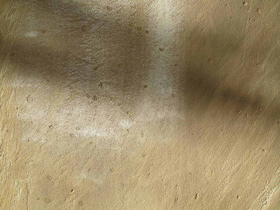 Sandy desert surface with shadows and light streaks