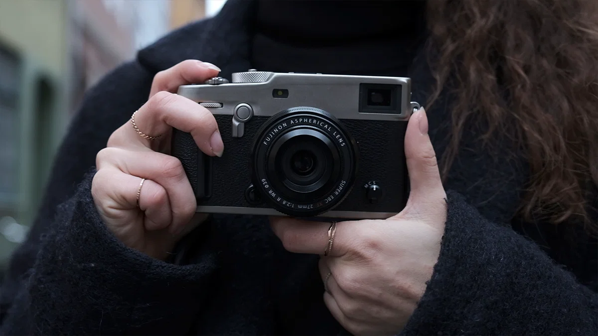 Компактна камера Fujifilm з об'єктивом-млинцем Fujinon XF 27mm f/2.8 R WR у руках людини на міській вулиці